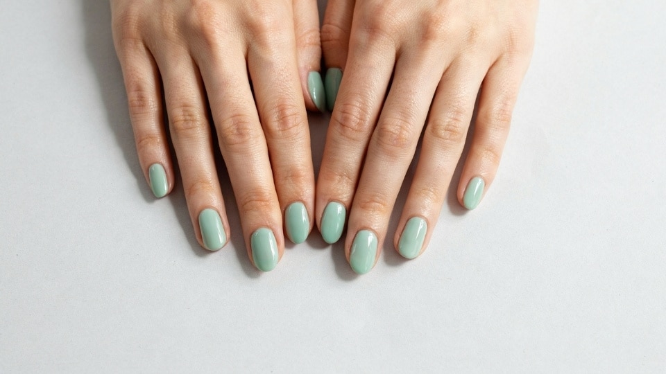 Hands displaying fresh mint green nails with a glossy pastel finish