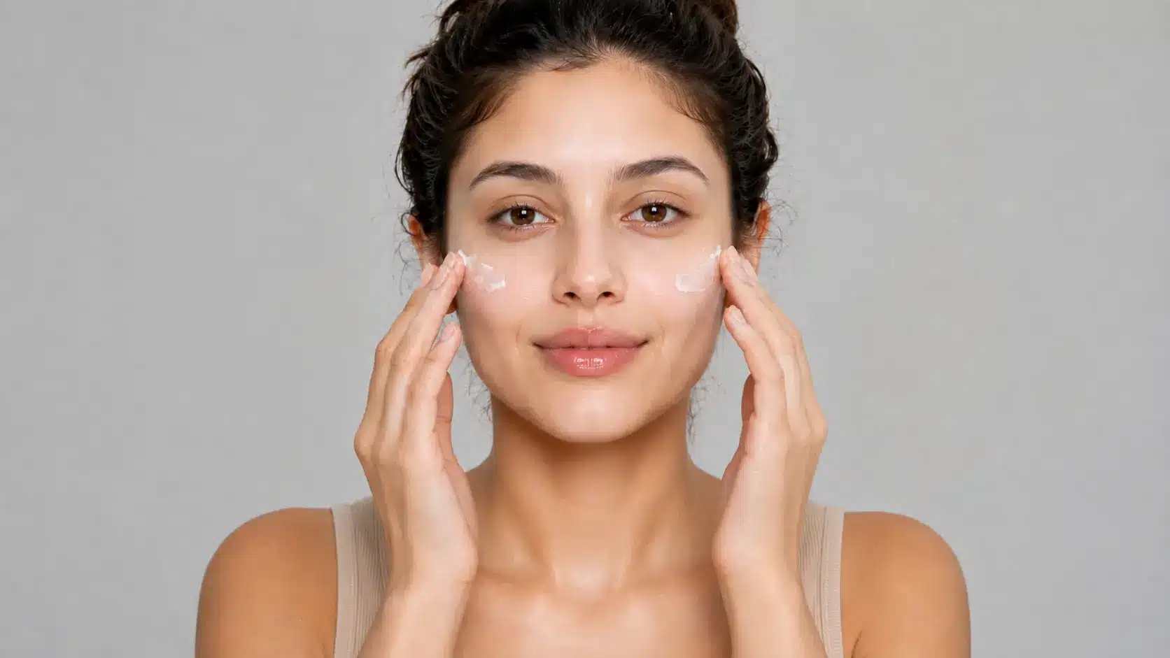 Woman applying moisturizer to hydrate her face before skeleton makeup.