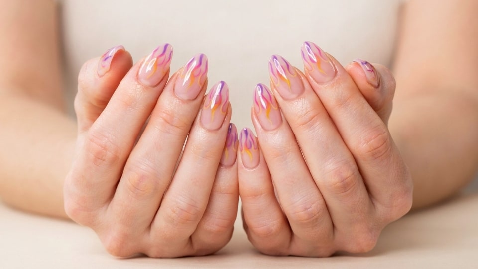 Neon flame nails with layered pink orange and yellow flame art creating a vibrant glossy manicure