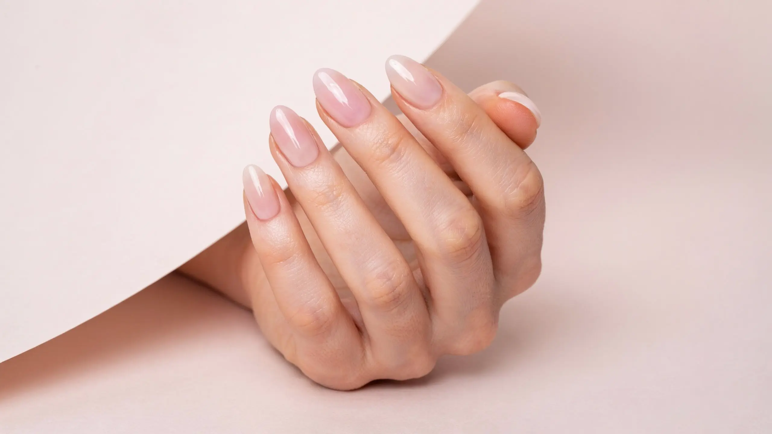 Hand with ombre clean girl nails blending sheer pink tones with a smooth glossy manicure finish