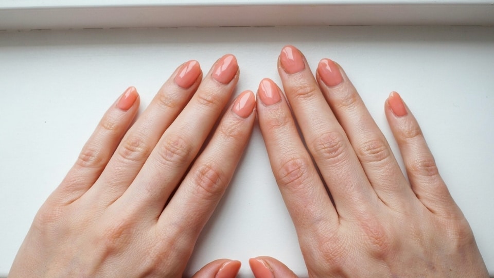 hands showing peach coral nails with warm pink orange tones