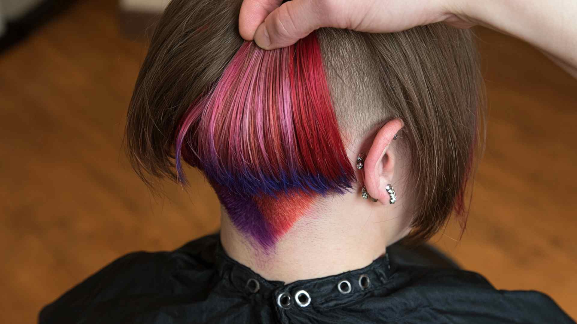 Short alternative haircut with hidden bold color revealed beneath the top layer