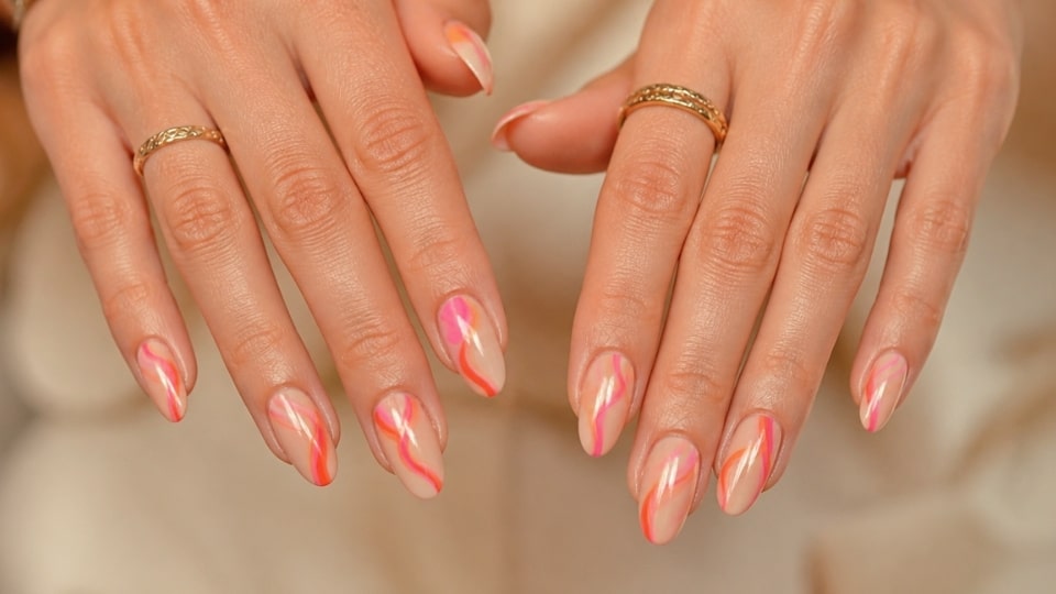 Pink and orange wave nails featuring curved flowing lines with bright colors over a clean glossy base