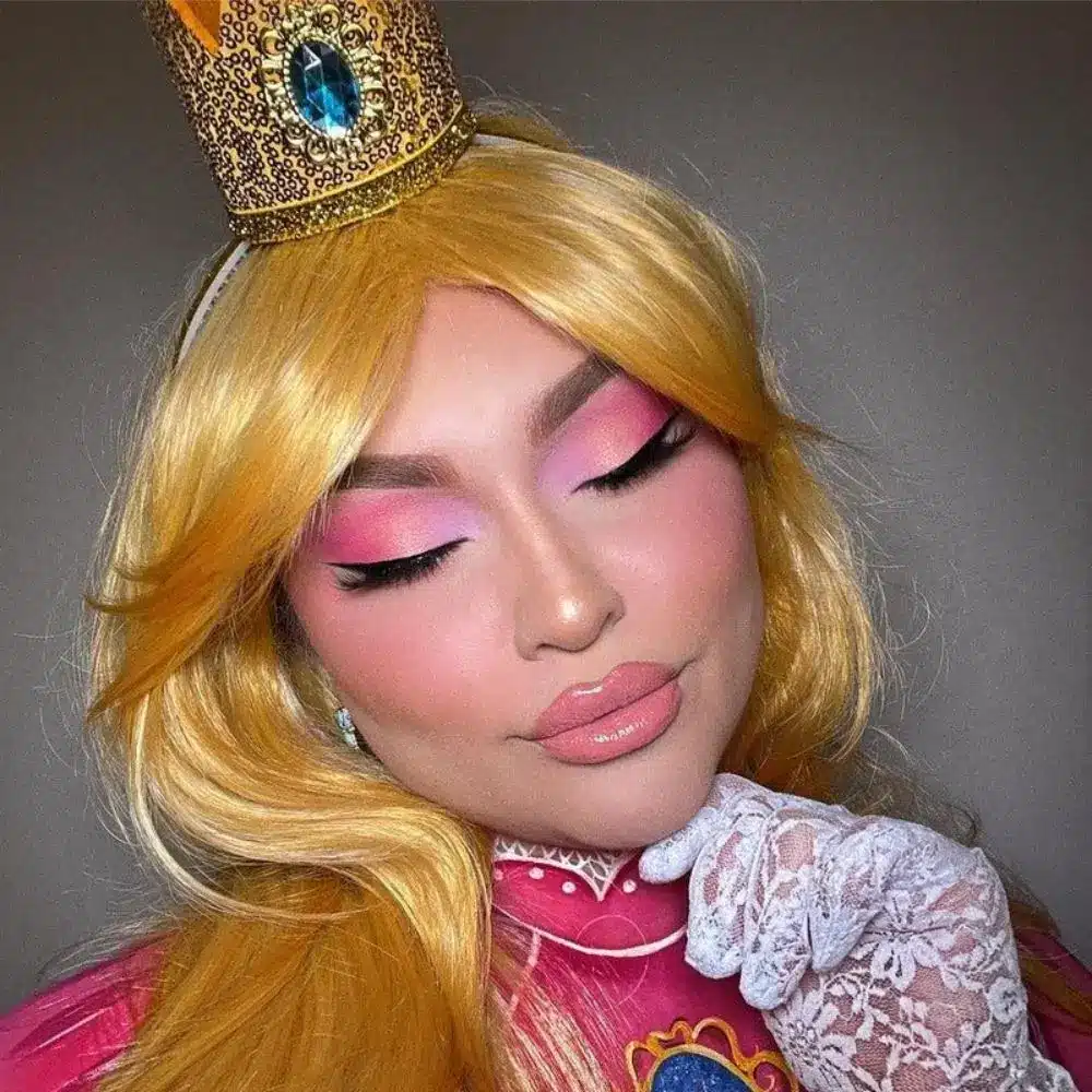 Princess Peach makeup with fresh skin, rounded pink eyeshadow, rosy blush, long soft lashes, and a classic pink lip
