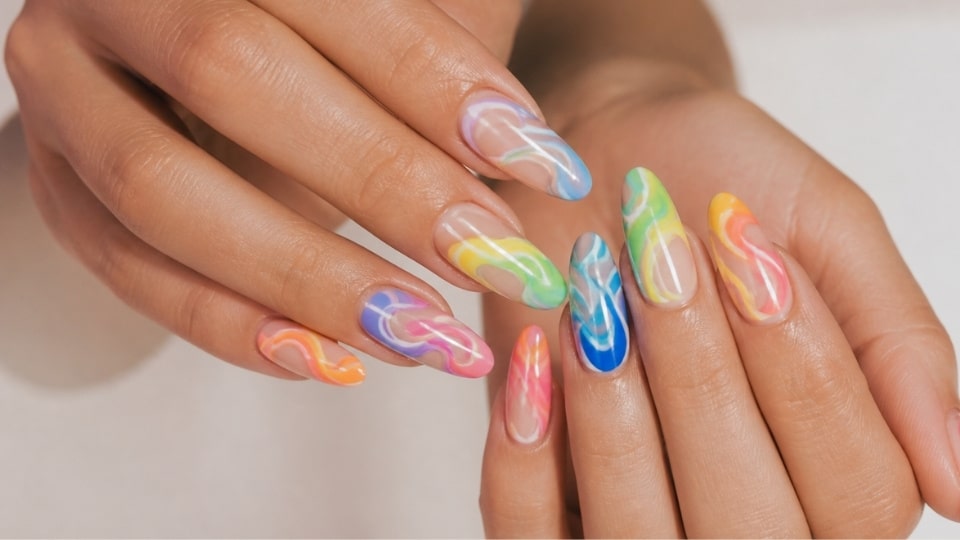 Rainbow swirl nails with flowing colorful patterns in pink orange blue green and purple over a glossy base