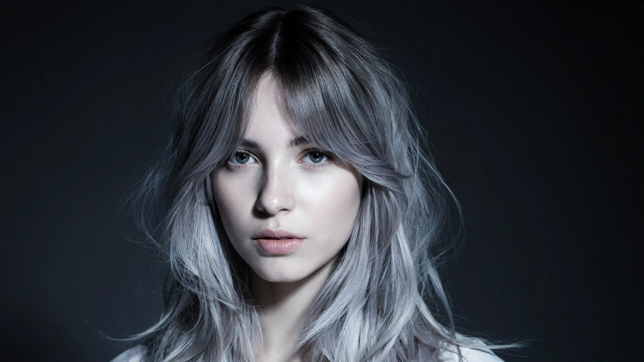 Silver gray hair with dark shadow roots creating contrast through a seamless blend into cool toned layered lengths