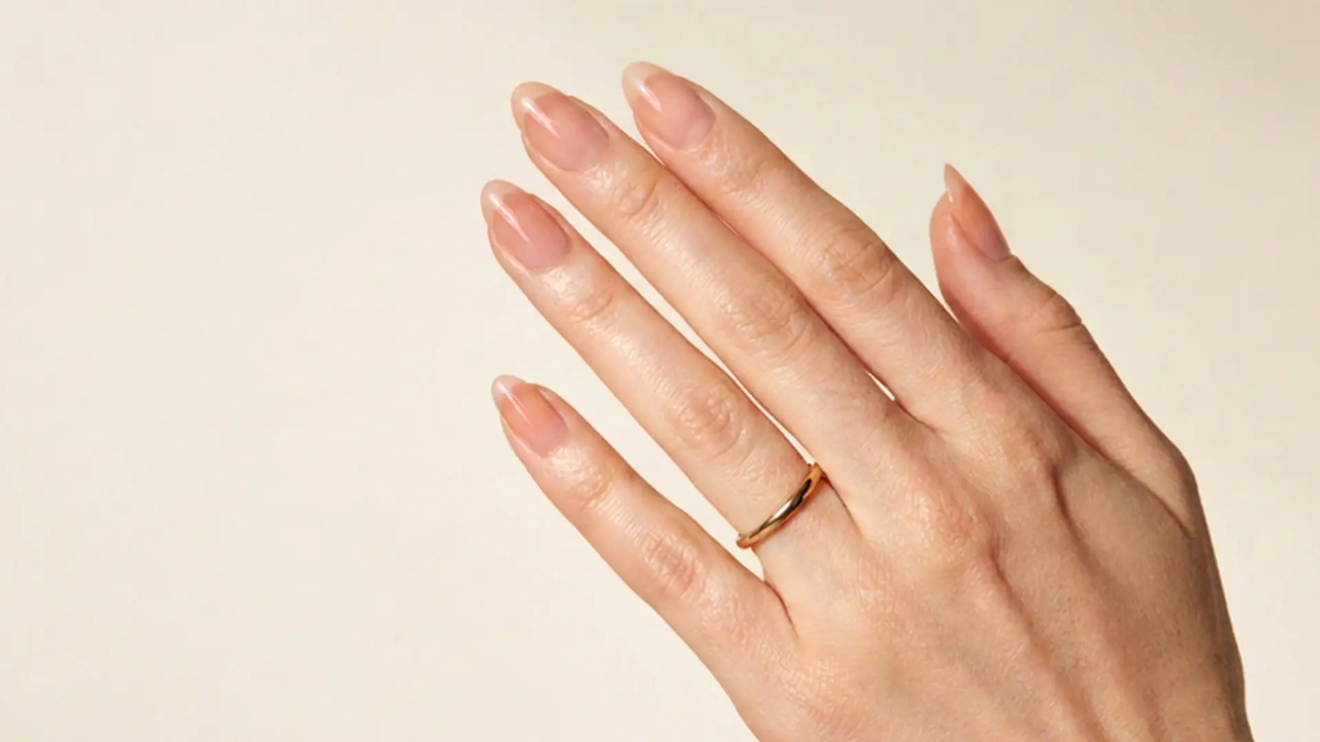 Close view of sheer apricot nails with glossy peach tones creating a soft natural manicure style