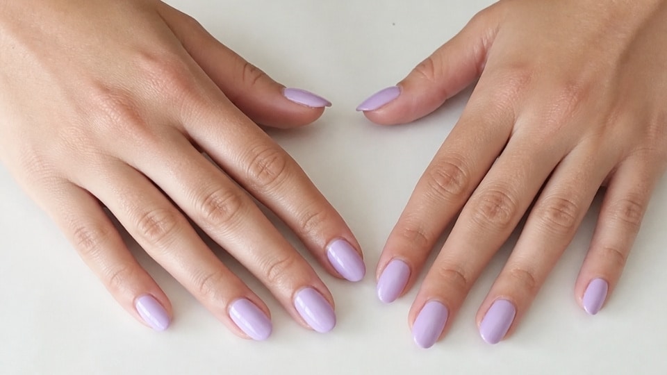 Feminine hands with soft lavender nails featuring a smooth pastel finish and clean minimal manicure design