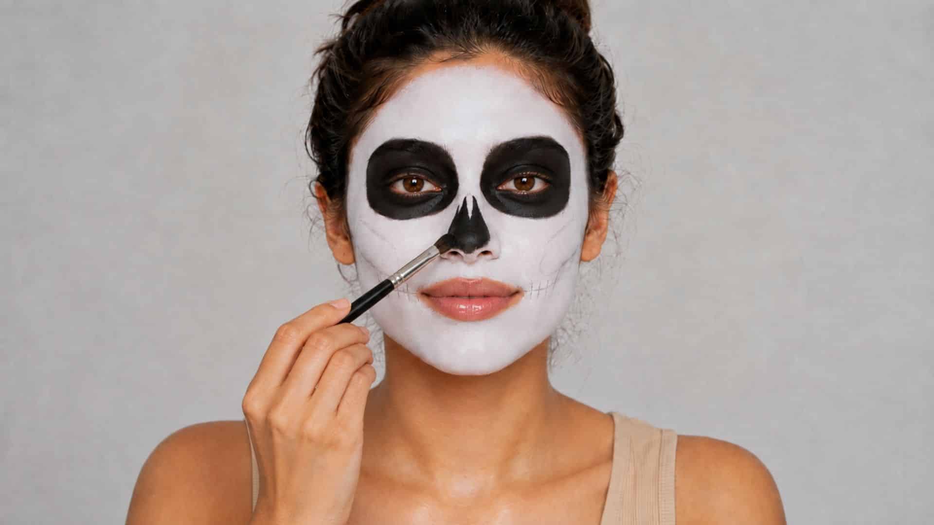 Woman adding a black skeletal nose shape with a small makeup brush.