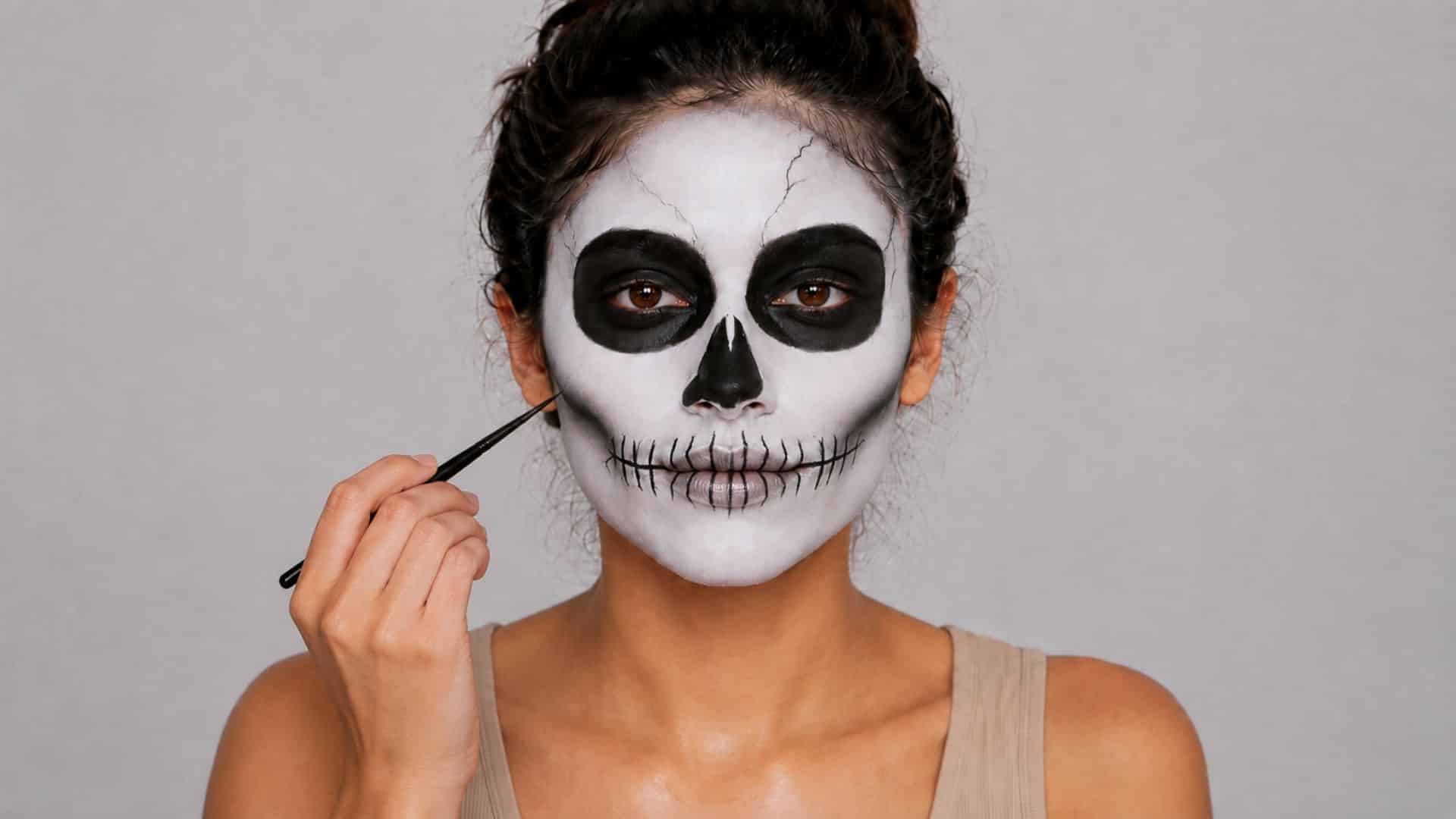Woman adding bone cracks and shading to her completed skeleton makeup.