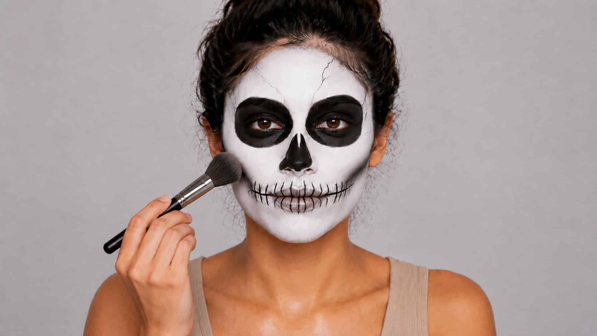 Woman setting her finished skeleton makeup with translucent powder.