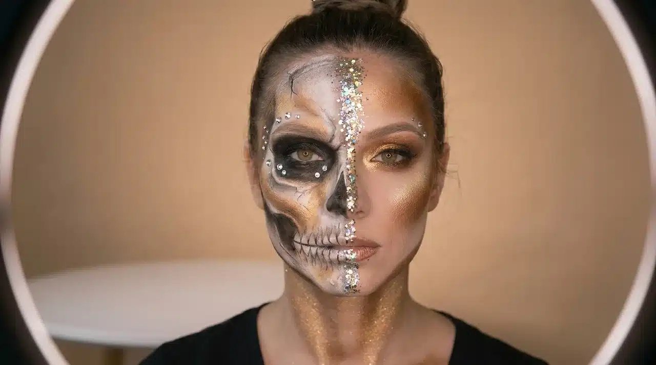 Front view of a woman with split face Halloween makeup showing realistic skull details and polished glam beauty styling