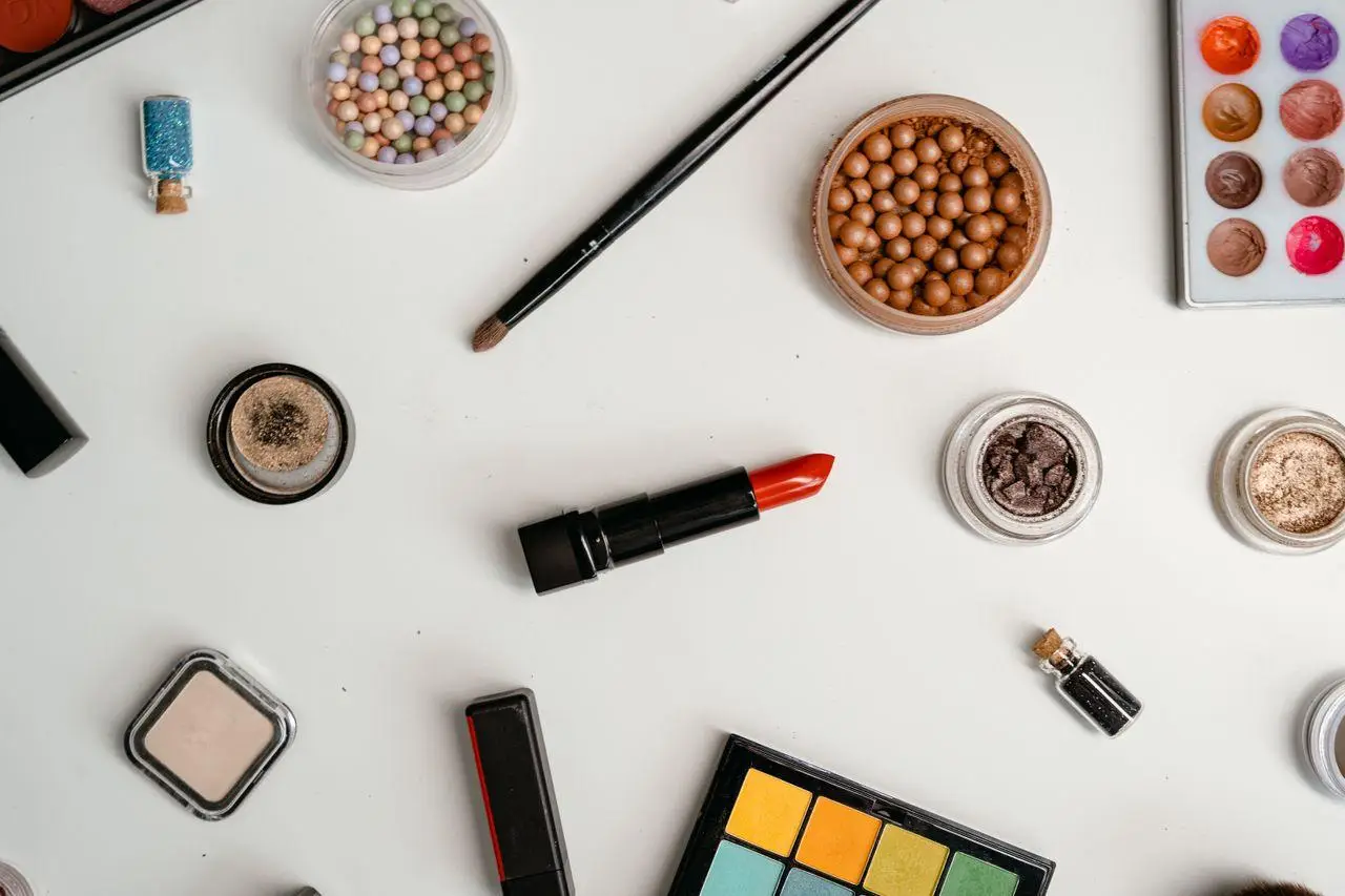 Assorted makeup items including lipstick and eyeshadow palettes on white surface