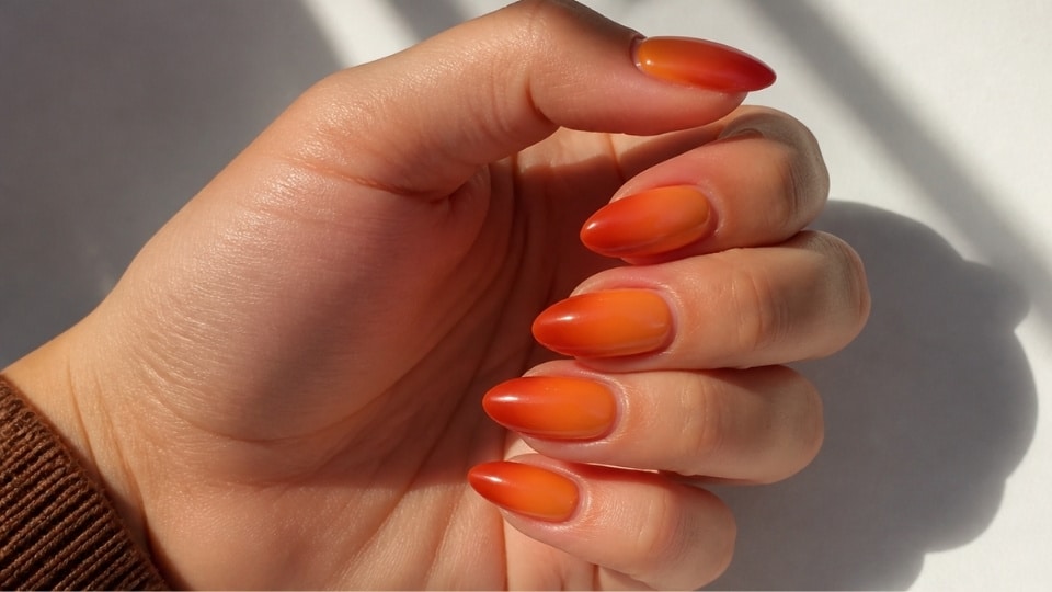 Tropical sunset ombre nails blending coral pink orange and yellow shades into a smooth glossy almond manicure