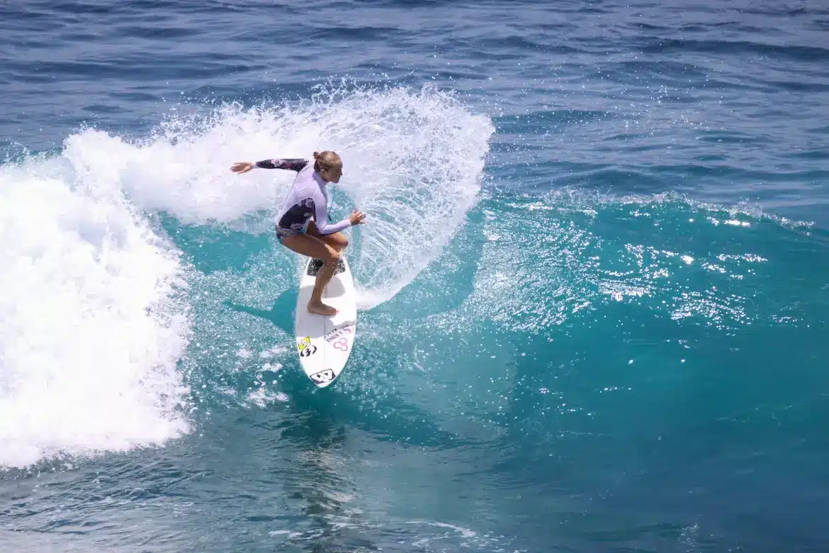 Surfer expertly riding a wave on a bright blue ocean under sunny skies