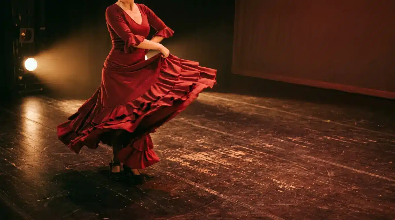 Dancer in red dress performing on dimly lit wooden stage